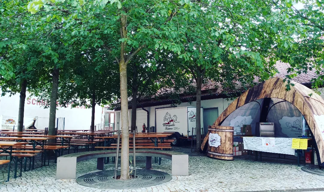 Außenbereich der Weinquelle Ranna mit Sitzplätzen und Weinfass